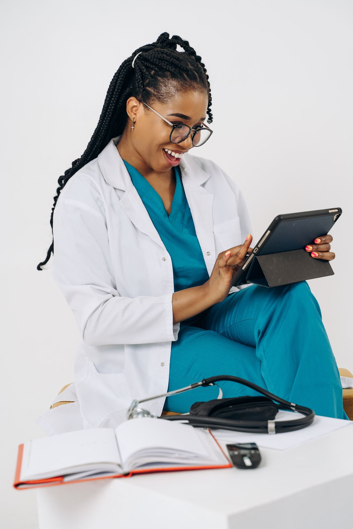 Une médecin en blouse blanche consulte une tablette en souriant.